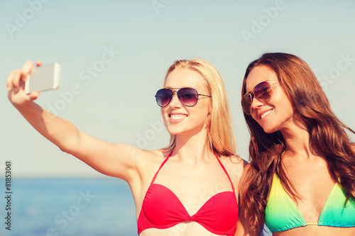 two smiling women making selfie on beach