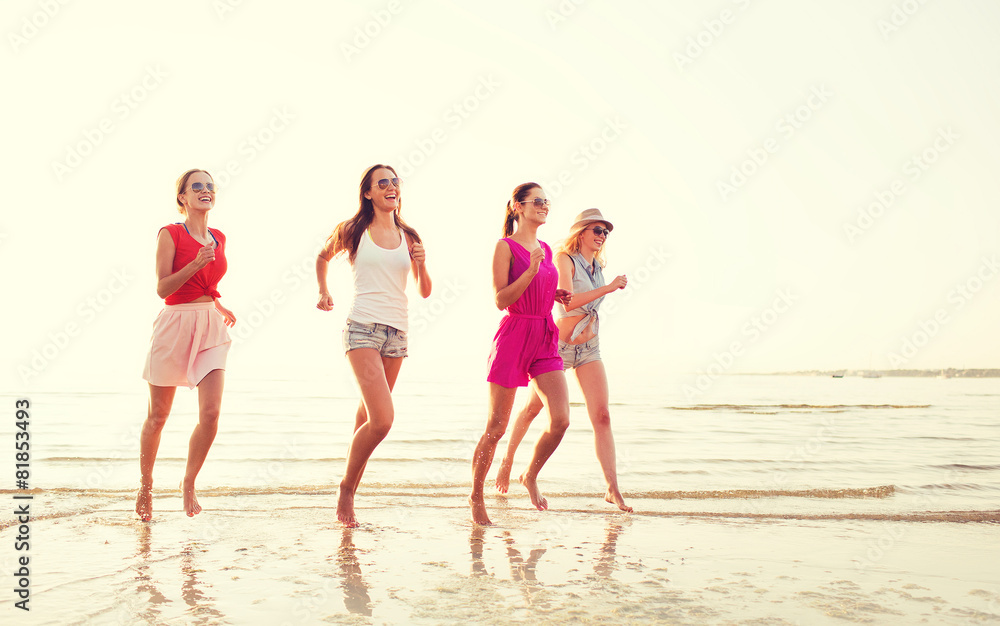group of smiling women running on beach