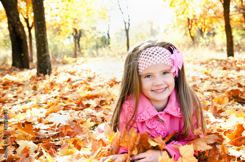 Autumn portrait of happy little girl with maple leaves