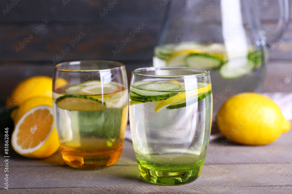 Fresh water with lemon and cucumber in glassware on wooden background Fresh water with lemon and cucumber in glassware on wooden background