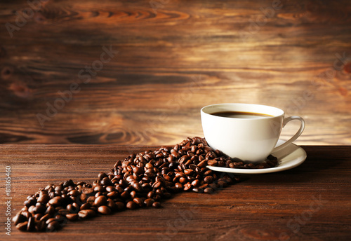 Cup of coffee with grains on wooden background