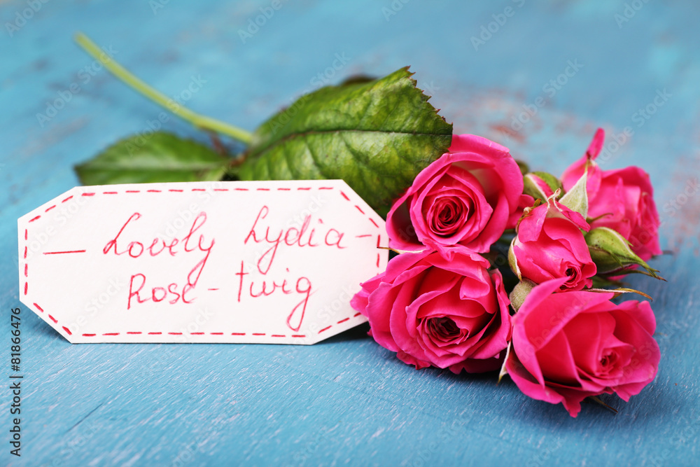 Beautiful rosy twig with tag on wooden background