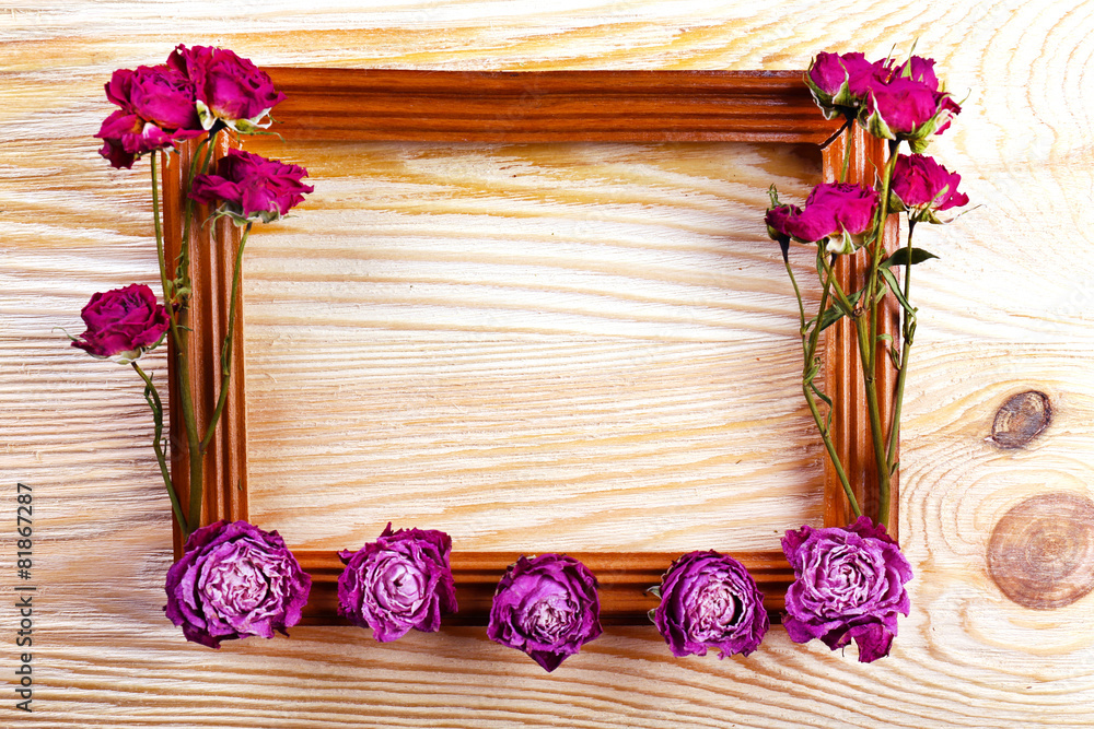 Photo frame with dried flowers on wooden background