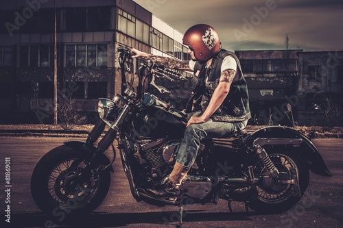Biker and his bobber style motorcycle on a city streets photo