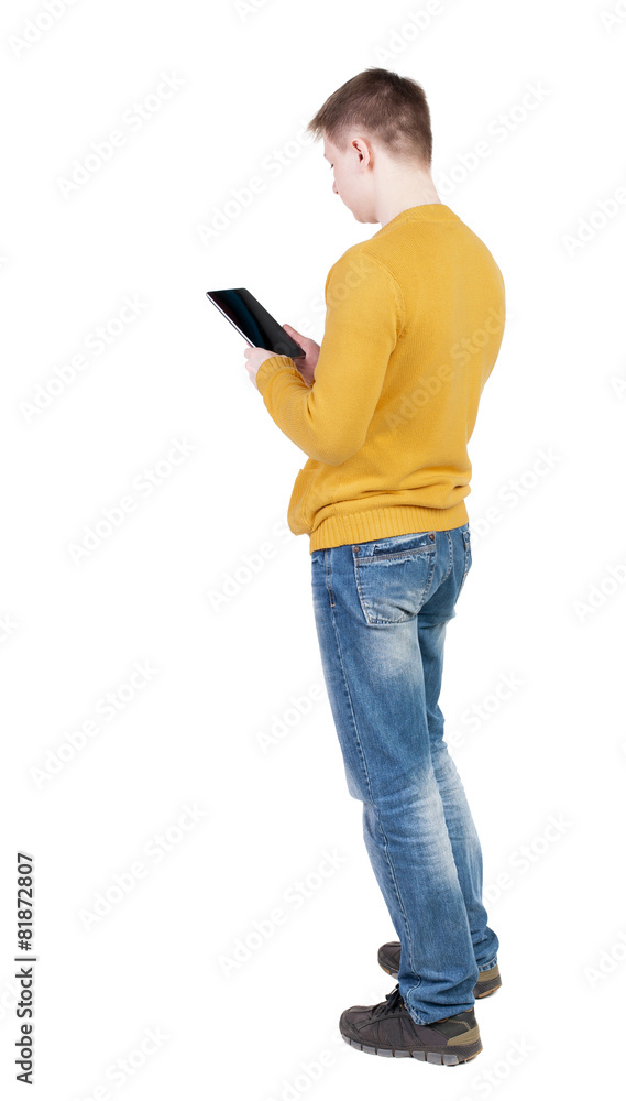 back view of standing young man with tablet computer in the hand back view of standing young man with tablet computer in the hand