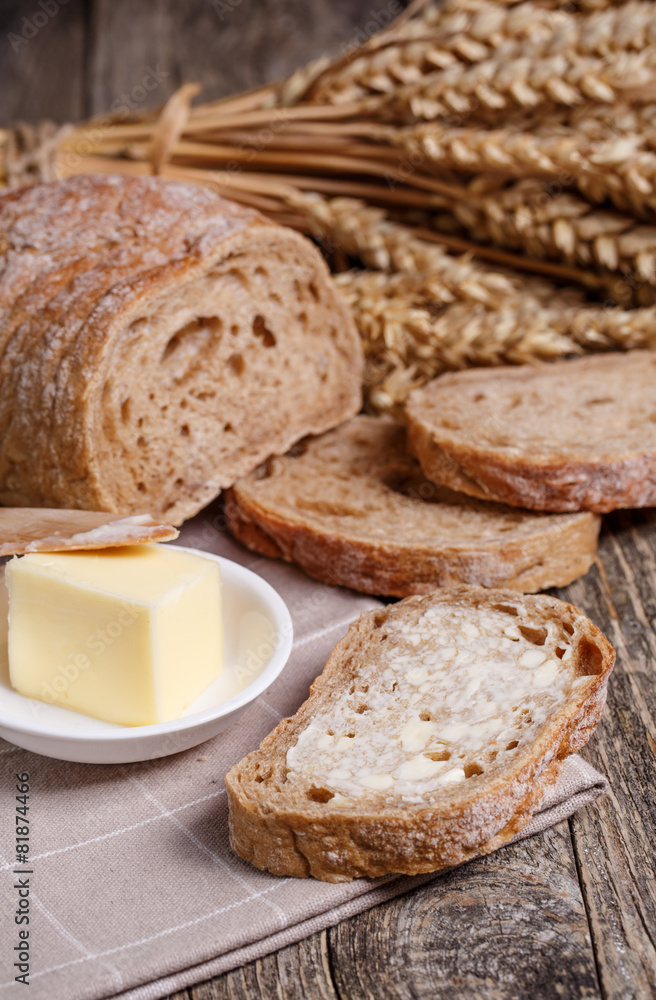 Tasty bread with wheat on wooden background.