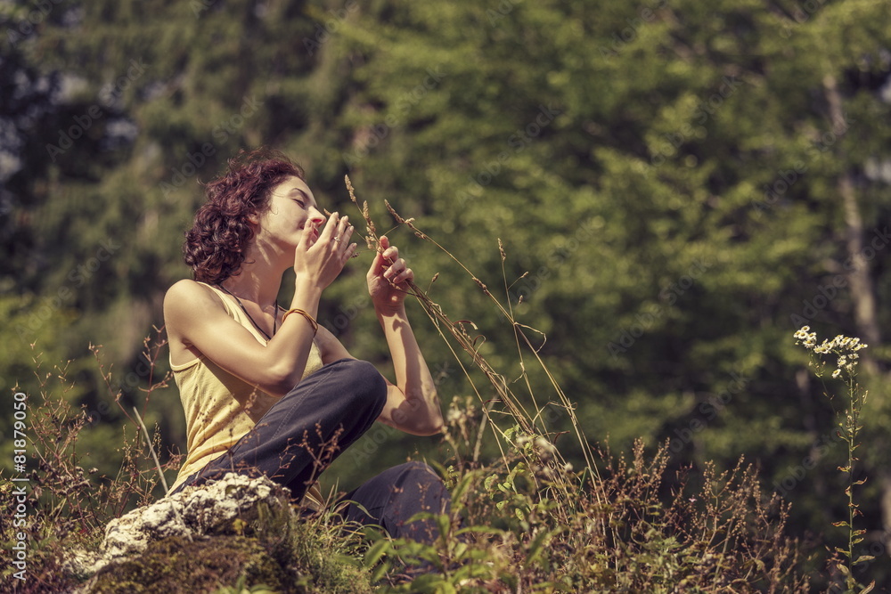 Fototapeta premium Peaceful woman gently touching and smelling wild mountain plants