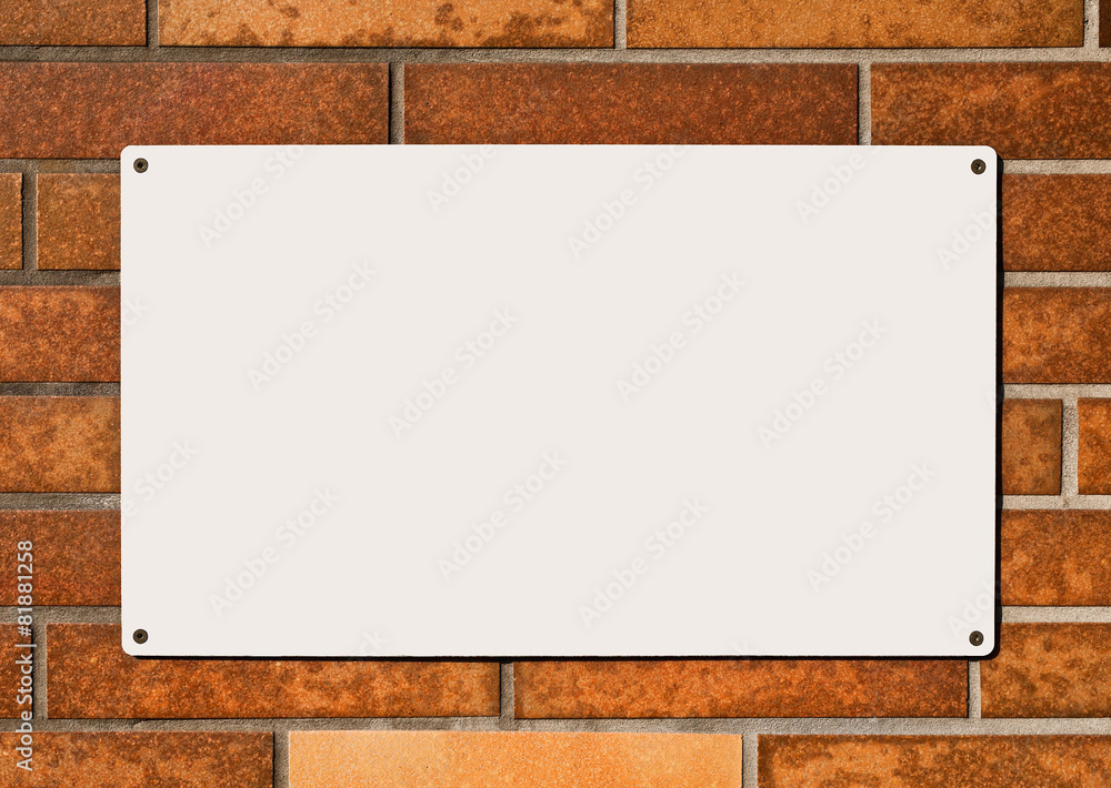 Ein leeres weisses Schild auf einer orange verklinkerten Wand Ein leeres weisses Schild auf einer orange verklinkerten Wand