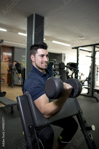 Young man training biceps at gym center