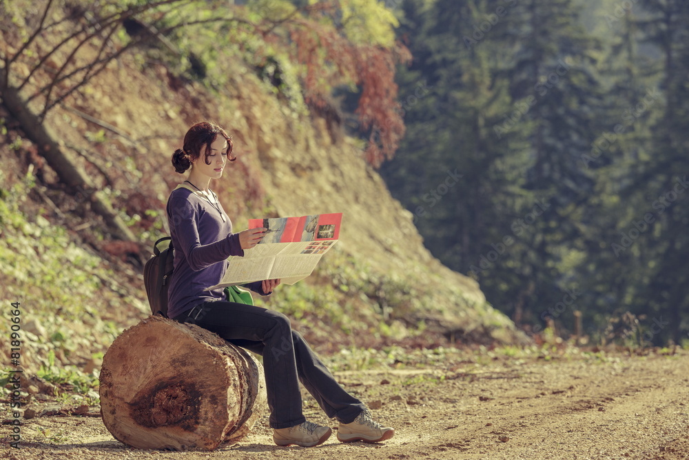 Young lady reading travel map during hike