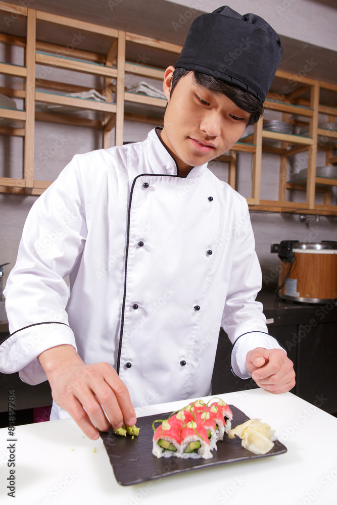 Cook adds wasabi and ginger to sushi rolls Cook adds wasabi and ginger to sushi rolls