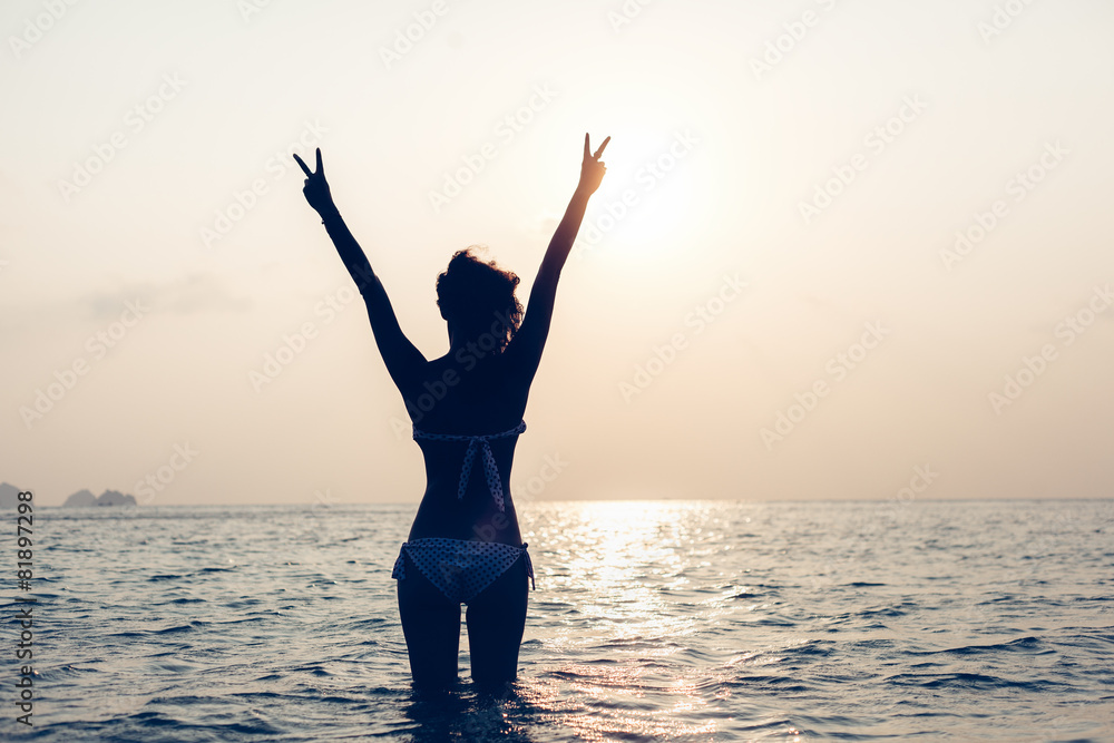 Fototapeta premium Young woman standing on beach and looking to sea