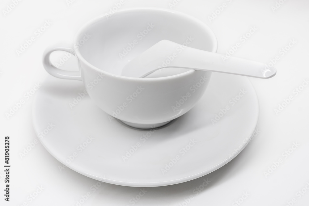 A white ceramic cup with saucer and soup spoon A white ceramic cup with saucer and soup spoon