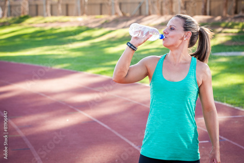 female athlete drinks from a bottle of water