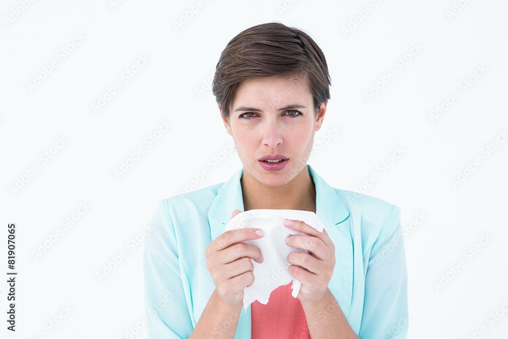 Sick woman holding a tissue and looking at camera Sick woman holding a tissue and looking at camera