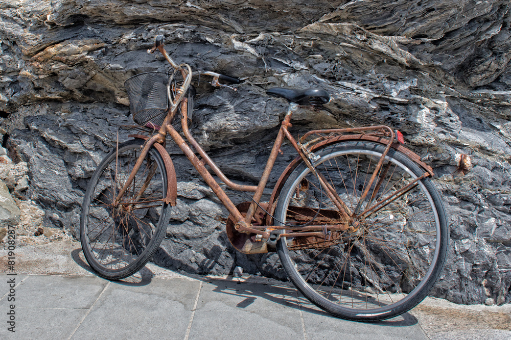 Naklejka premium rusted bycicle on rocks background