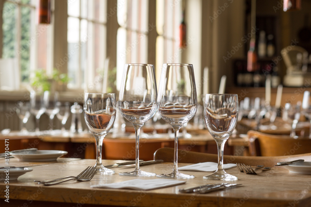 Gläser vor Restaurant Kulisse auf Holztisch // leer Gläser vor Restaurant Kulisse auf Holztisch // leer