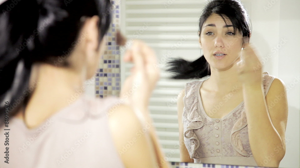 Beautiful happy young lady putting makeup in front of mirror Beautiful happy young lady putting makeup in front of mirror