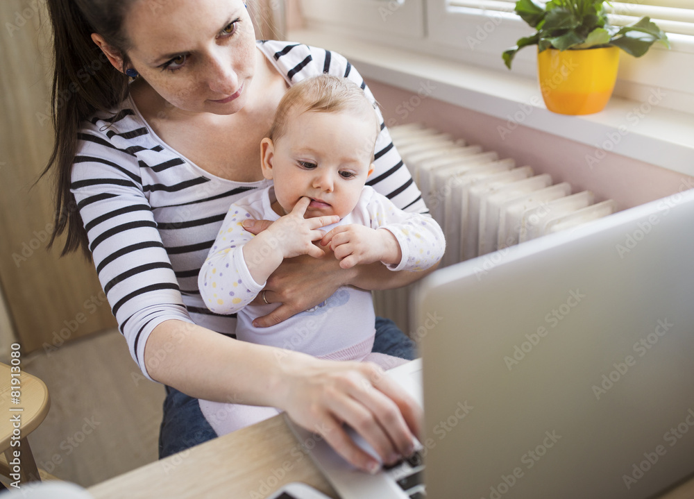 Young mother in home office with computer and her daugher Young mother in home office with computer and her daugher