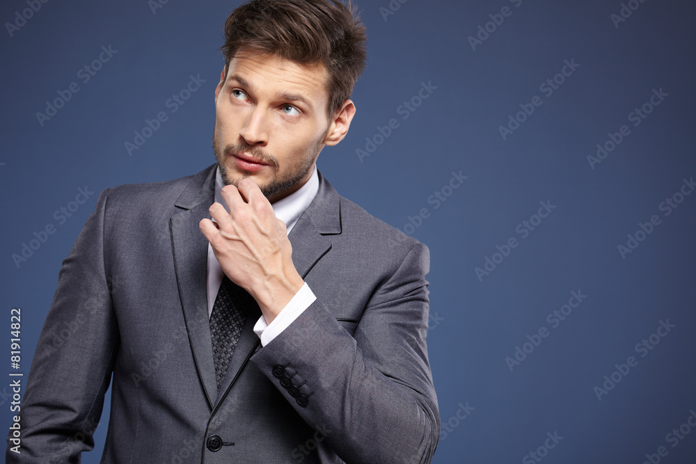 Handsome young business man standing on blue background Handsome young business man standing on blue background