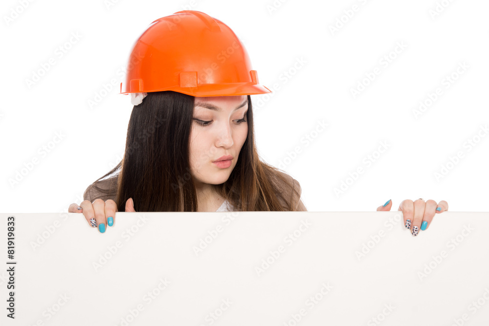 Girl builder in helmet looking at a blank banner Girl builder in helmet looking at a blank banner