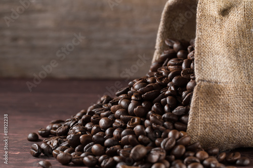 jute bag full of roasted coffee beans and scattered on a wooden table