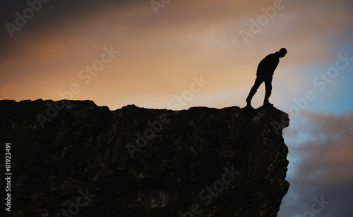 Silhouette of man standing on top of mountain looking down