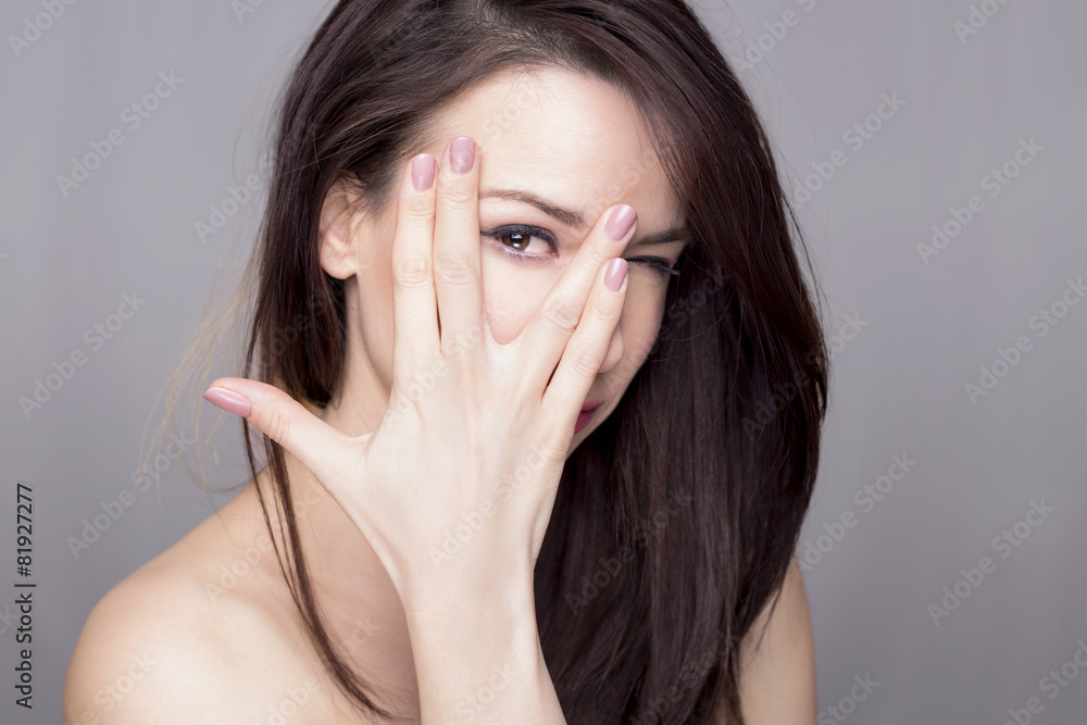Pretty woman peeking through her fingers Pretty woman peeking through her fingers