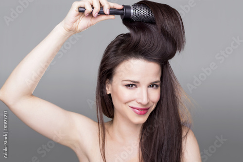 Gorgeous girl smiling and holding a hair brush in her hair