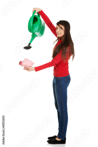 Woman watering piggybank.