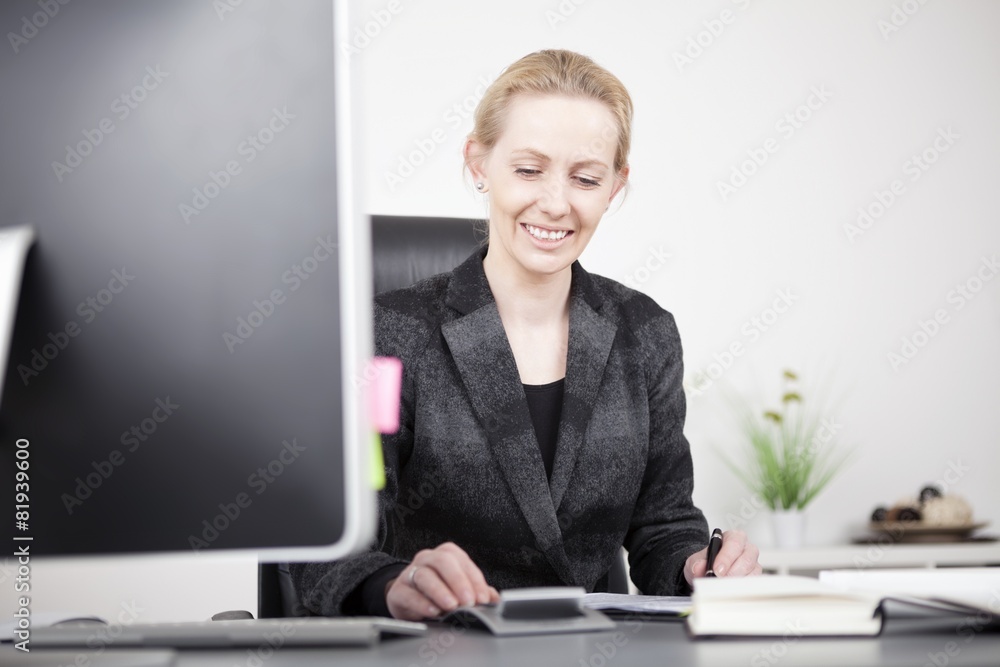 Happy Businesswoman Calculating at her Worktable