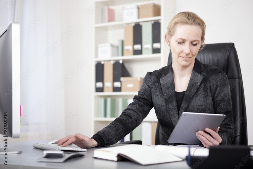 Manageress with Tablet Typing on Desktop Computer Manageress with Tablet Typing on Desktop Computer