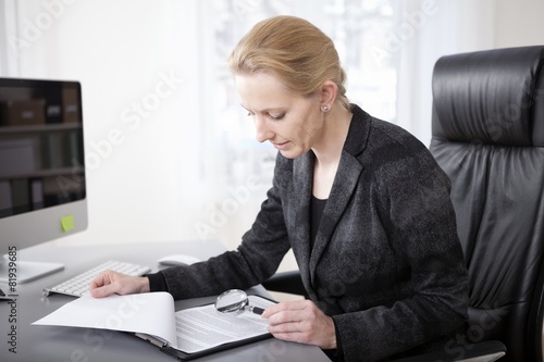 Manageress Scanning Papers with Magnifying Glass