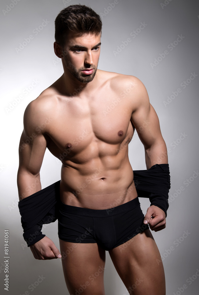 Fototapeta premium handsome young bodybuilder showing of his fit body and muscles