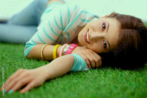 Beautiful young woman lying on green grass
