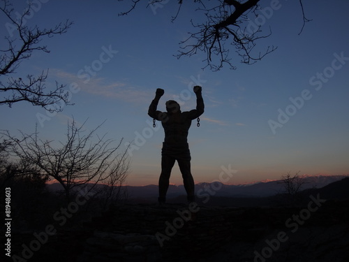 Силуэт человека на фоне синего закатного неба и горных вершин