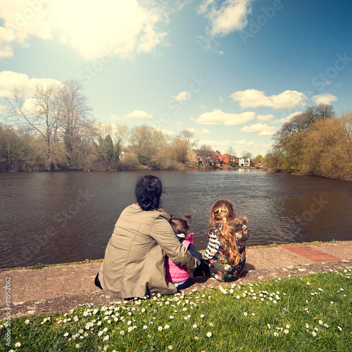 mother and two doters relaxing next to river photo