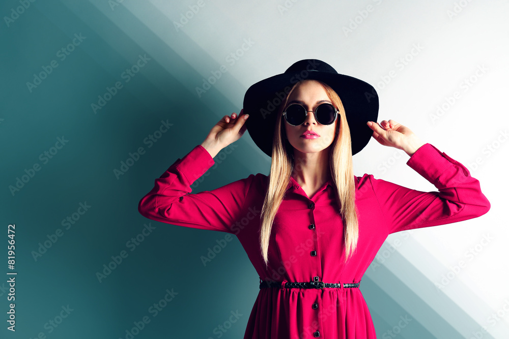 Expressive young model with hat and sunglasses on wall background Expressive young model with hat and sunglasses on wall background