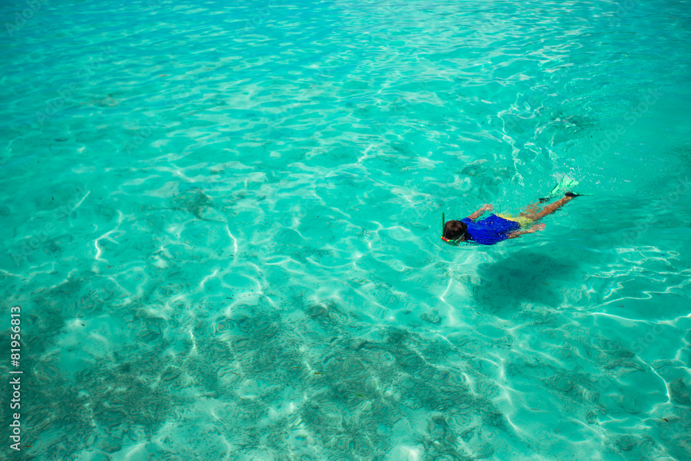 Young man snorkeling in clear tropical turquoise waters