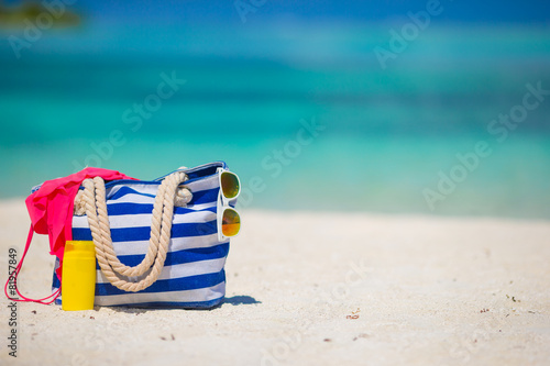Blue bag, swimsuit, sunglasses and suncream on white beach © travnikovstudio