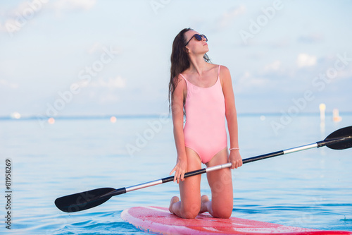 Photography Beautiful young woman surfing on stand up paddle board at exotic