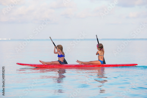 Little girls swimming on surfboard during summer vacation © travnikovstudio