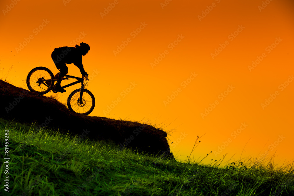 Fototapeta premium silhouette of downhill mountain bike ride at sunset