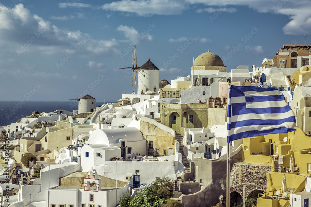 Village of Oia against greek waving flag, Santorini ,Greece