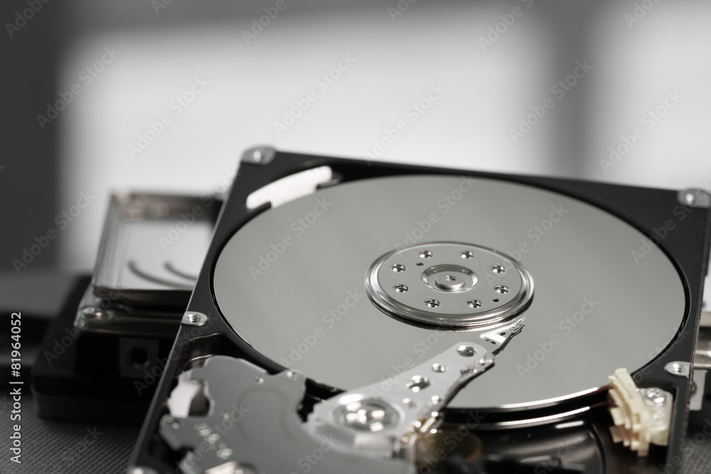 Close up of open computer hard disk drive on desk and notebook Close up of open computer hard disk drive on desk and notebook