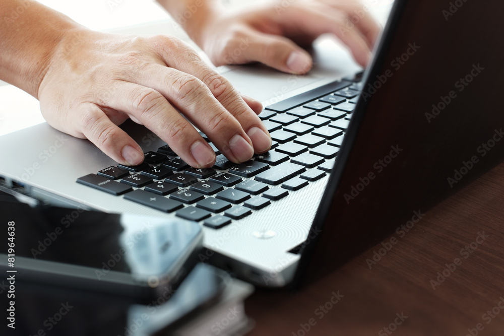 Close up of business man working on laptop computer on wooden de Close up of business man working on laptop computer on wooden de