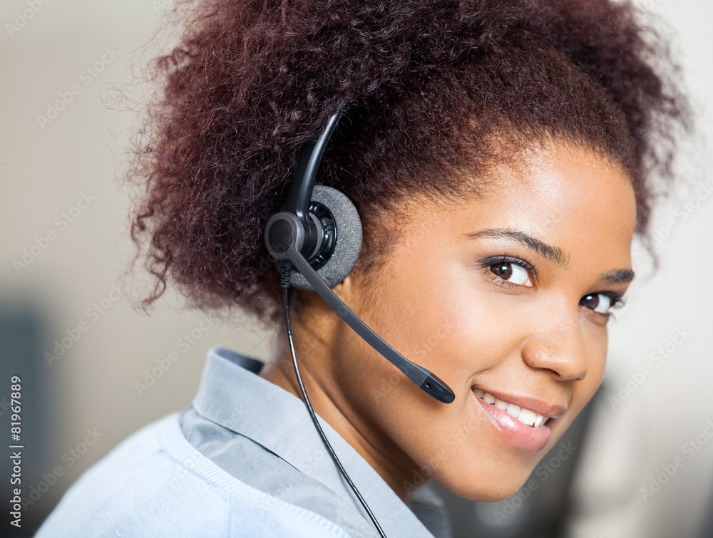 Confident Female Customer Service Agent Wearing Headset At Desk Confident Female Customer Service Agent Wearing Headset At Desk