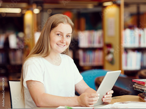 Teenage girl with tablet in library