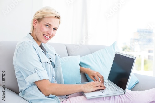 Pretty blonde woman using her laptop on the couch