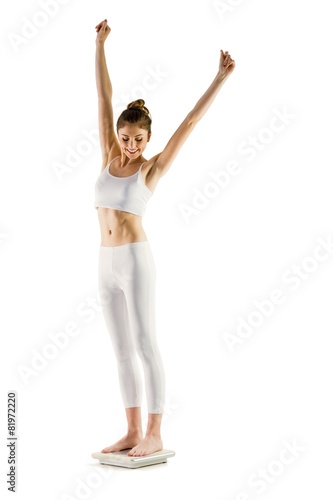 Fototapeta Naklejka Na Ścianę i Meble -  Slim woman cheering on scales